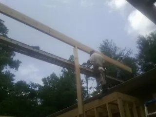Carpenter setting a ridge beam over a new addition frame — Ice Dam Removal by Roofing Brothers in Ashton