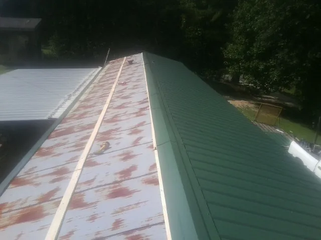 Old rusted panels beside newly installed green metal roofing — Wind Damage Roof Repair by Roofing Brothers in Ashton