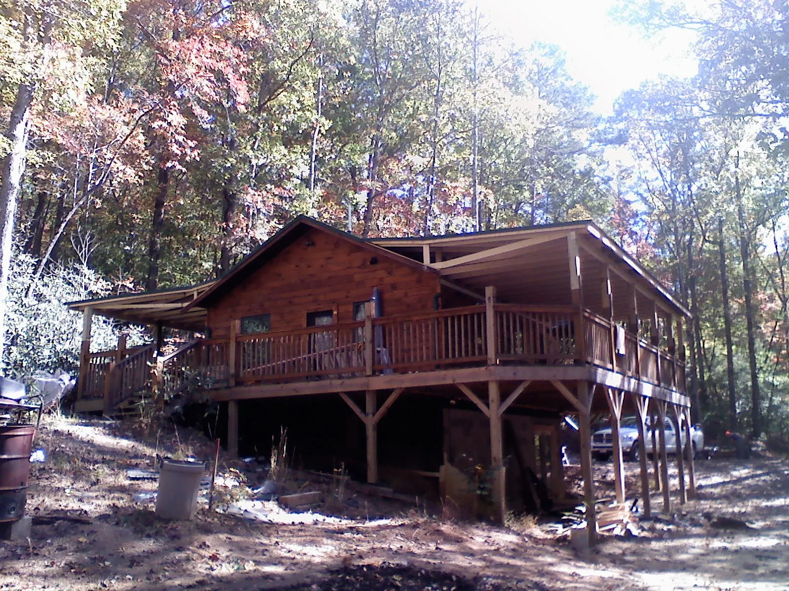 Log cabin with a wraparound porch and metal roof in the fall in Ashton
