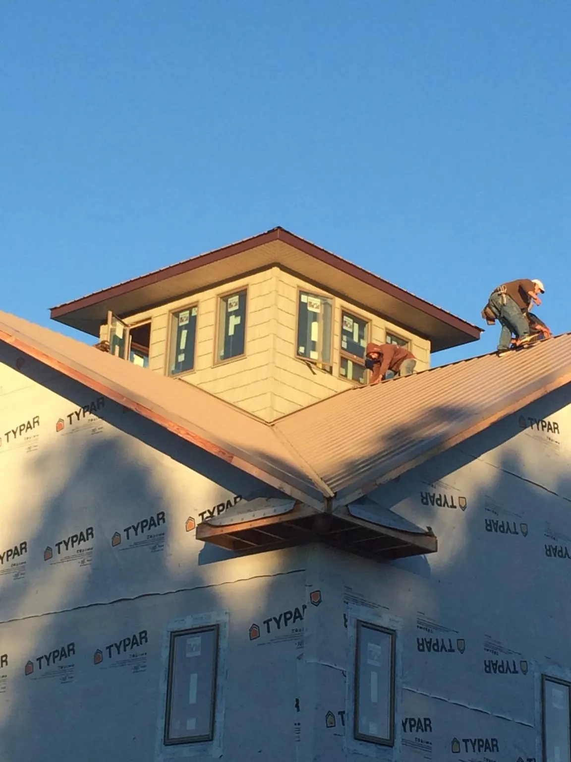 Roofers working around a rooftop cupola on a new metal roof at sunset — Roof Waterproofing in Ashton by Roofing Brothers